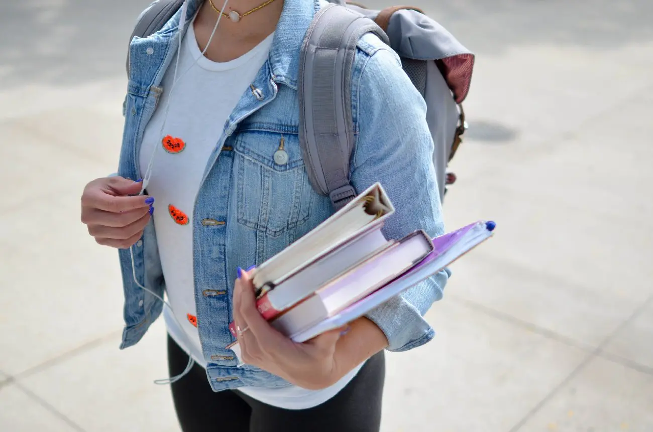Student holding books and carrying backpack