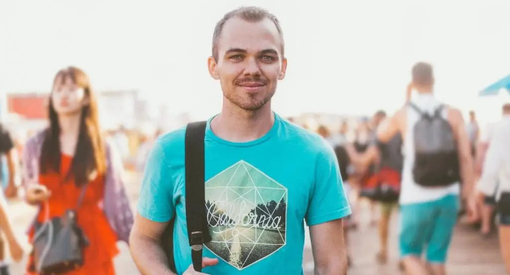 A man with a bag smiling at the camera