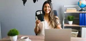 a woman holding a passport and boarding pass while sitting in a table