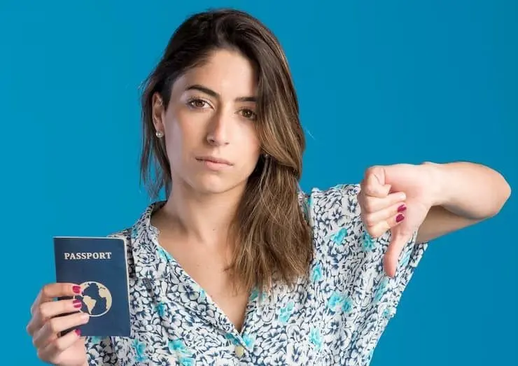 a woman showing a thumbs down gesture while holding a passport