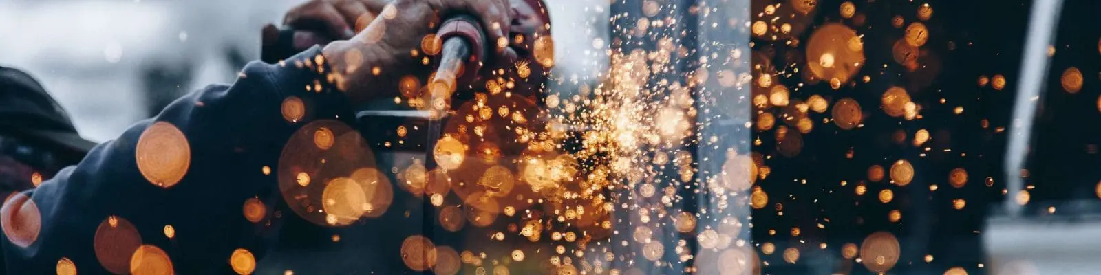 hands working in a factory with orange sparks