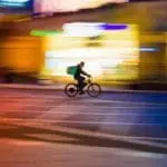 Food delivery worker on bike in London streets at night