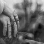 an older couple wearing wedding rings and holding hands