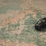 Black Toy Car on World Map Paper close to Sweden