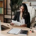 woman in office looking at papers with laptop on desk