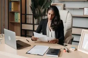 woman in office looking at papers with laptop on desk