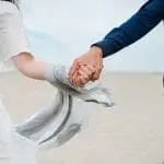 a couple holding hands at the beach