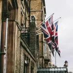two UK flags hoisted on a balcony