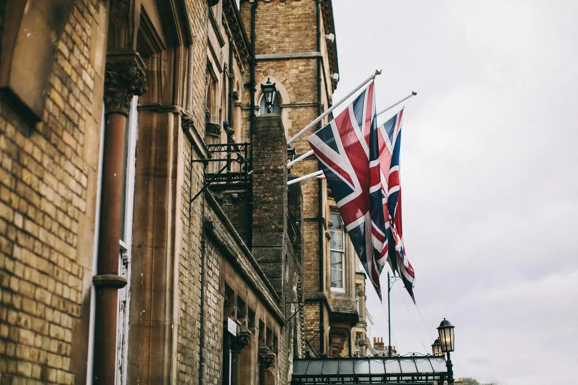 two UK flags hoisted on a balcony