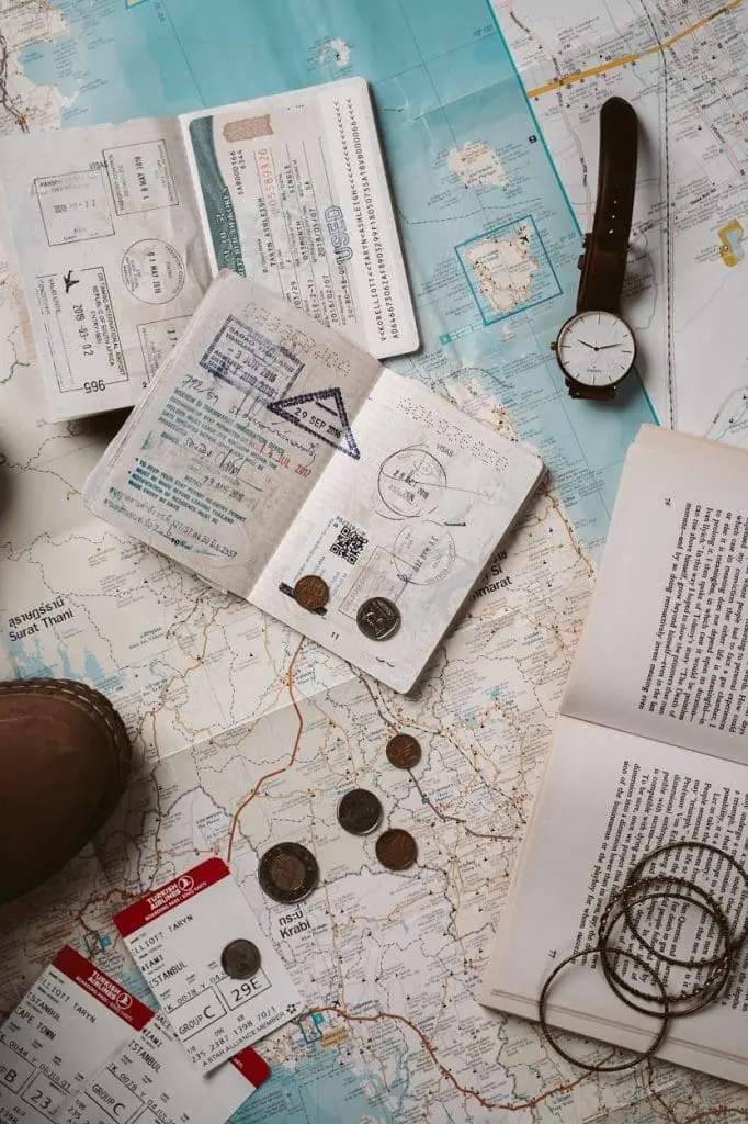 map, passport, coins and watch on a table