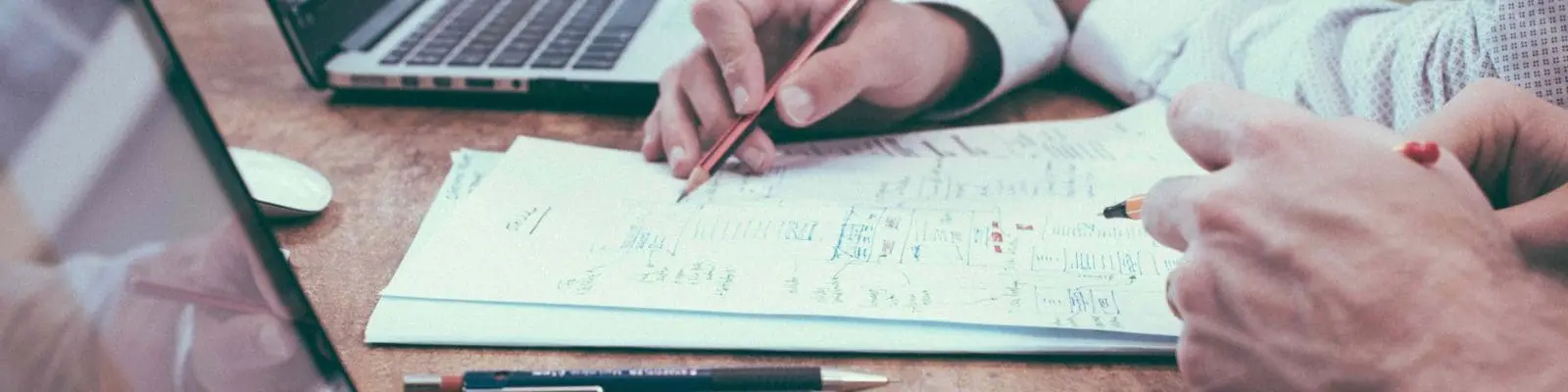 someone writing on a desk with a laptop beside them as an example of the english language test