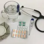 Stethoscope by mug of water and pills