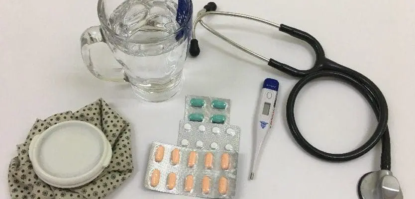 Stethoscope by mug of water and pills