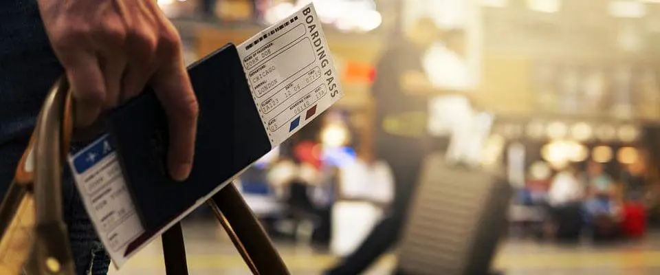 someone holding a boarding pass, passport, and travelling bag