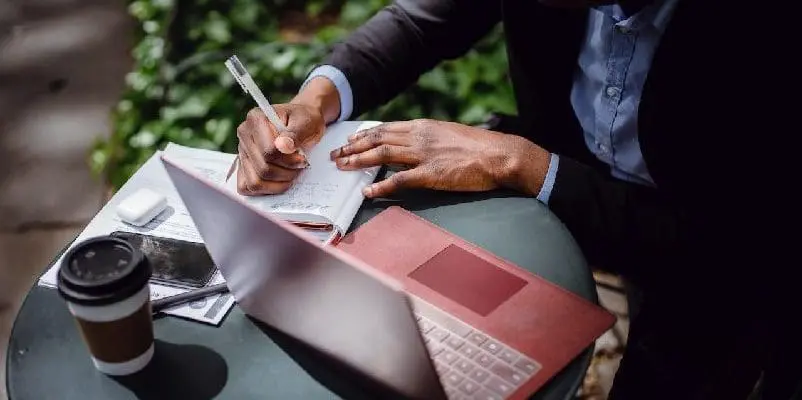 Man sitting at table with notebook and laptop