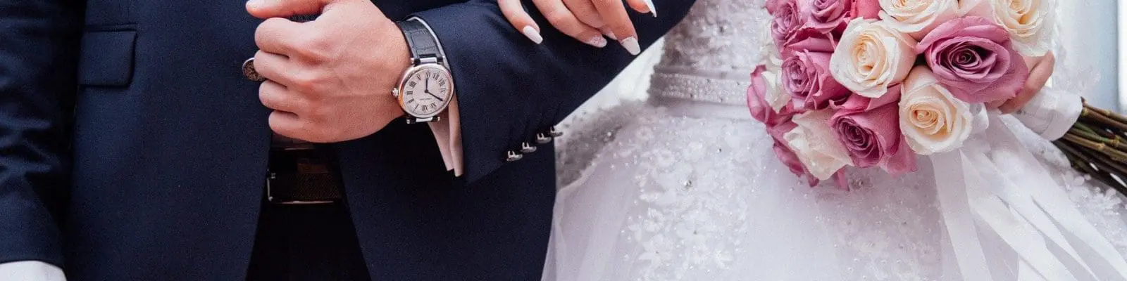 a couple in a wedding dress and suit. The bride is holding a boquet