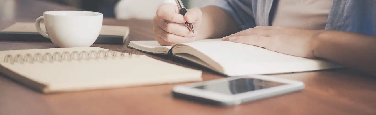 woman writing in a notebook to represent an application being filled out.