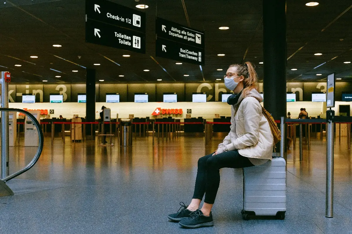 Adult sitting on suitcase at airport