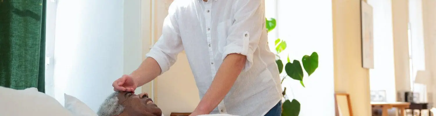 Caregiver checking man's temperature.