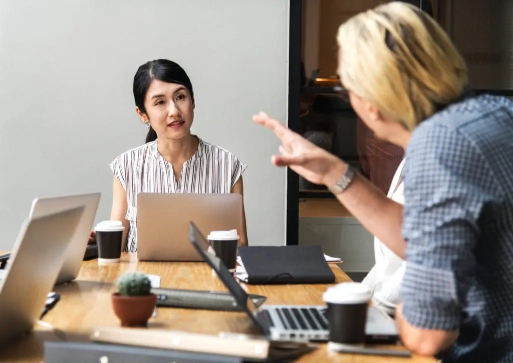 two members of staff seen in discussion during a meeting