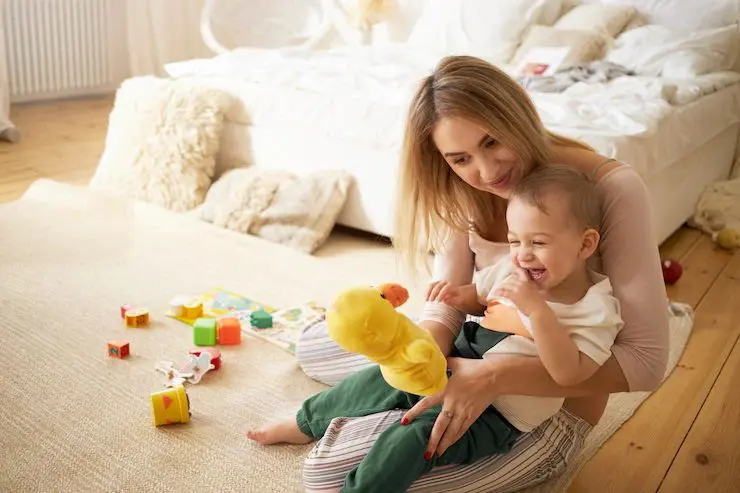 Woman with baby, playing with toy.