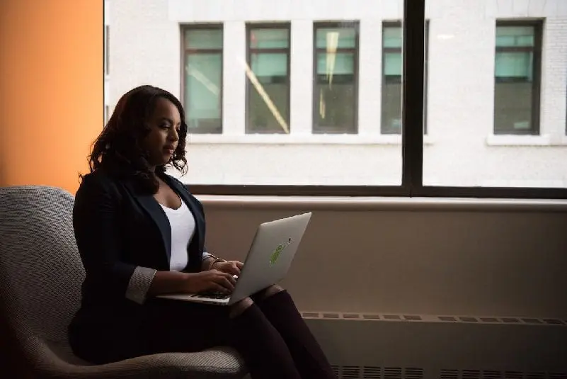 Woman sitting by window, using laptop