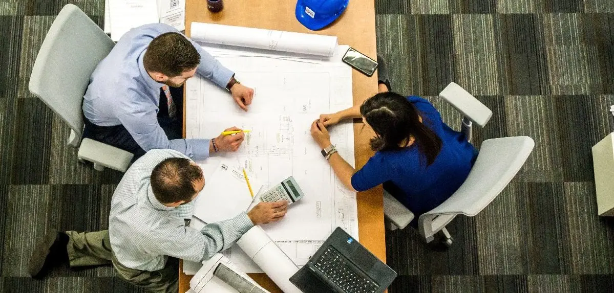 3 adults around a table discussing work matters