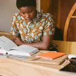 Woman sitting at desk, reading a book
