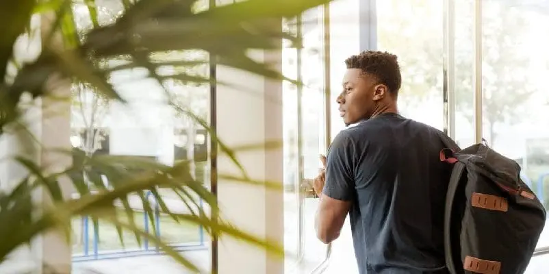 Student stepping outside, through glass door