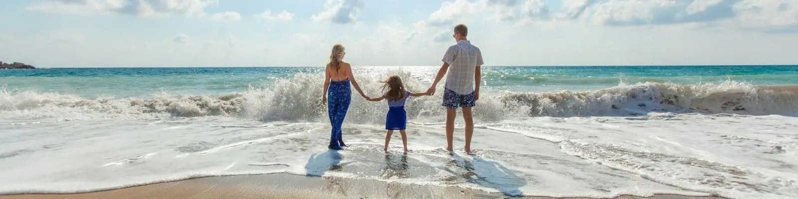 Family holding hands on beach by sea