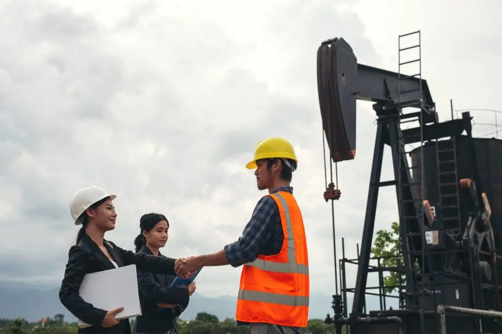 employees standing beside an oil pump