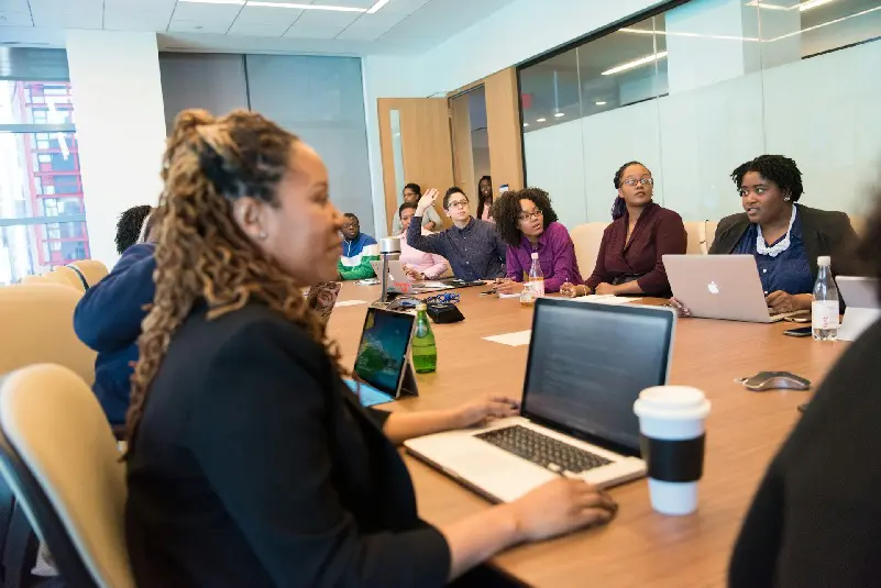 Staff members sitting around table, using laptops