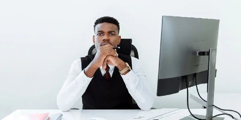 Man sitting at desk with computer and notebook