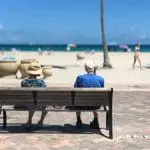 Elderly, retired couple sitting on a bench at the beach