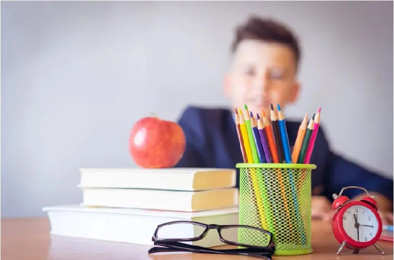 Schoolboy sitting at desk with studying utensils