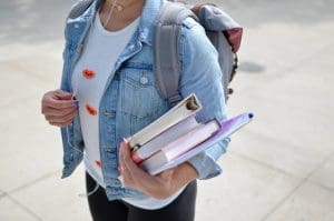 Student holding books and carrying backpack