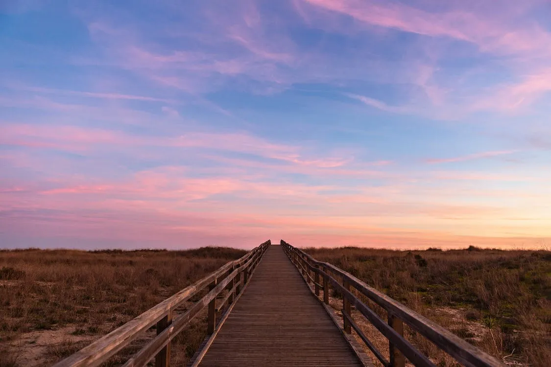 wooden bridge stretching out into sunset