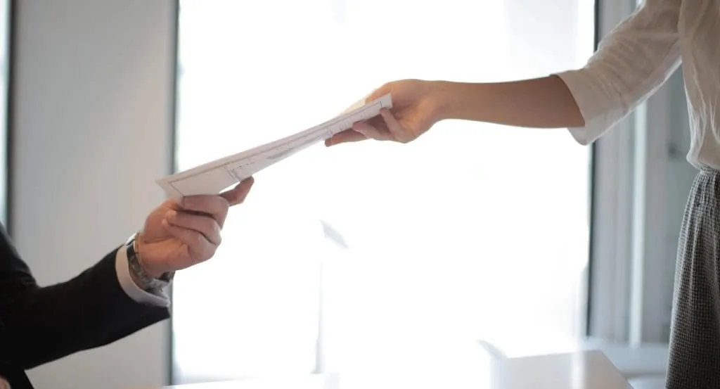 two employees handing documents