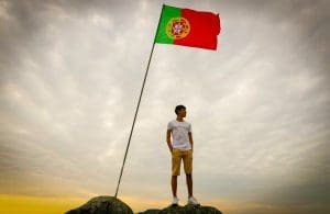 a man standing beside a flag of Portugal
