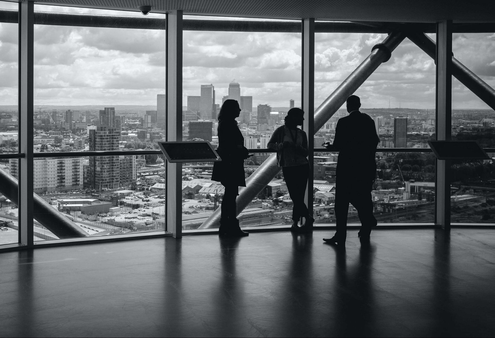 people standing inside a city building overlooking canary wharf