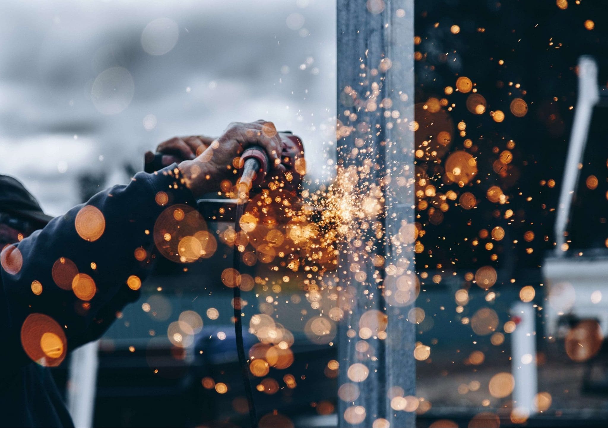 hands working in a factory with orange sparks