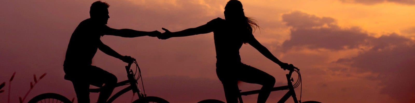 adults holding hands and riding separate bicycles