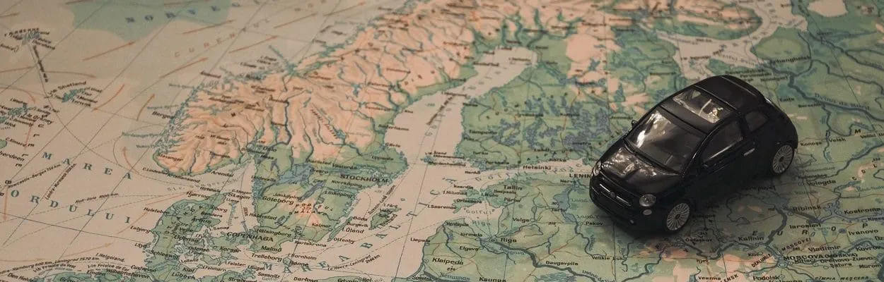 Black Toy Car on World Map Paper close to Sweden
