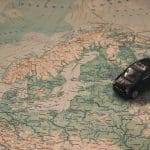 Black Toy Car on World Map Paper close to Sweden