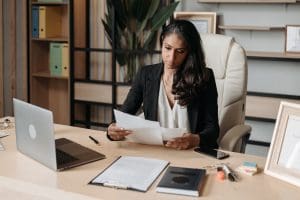 woman in office looking at papers with laptop on desk