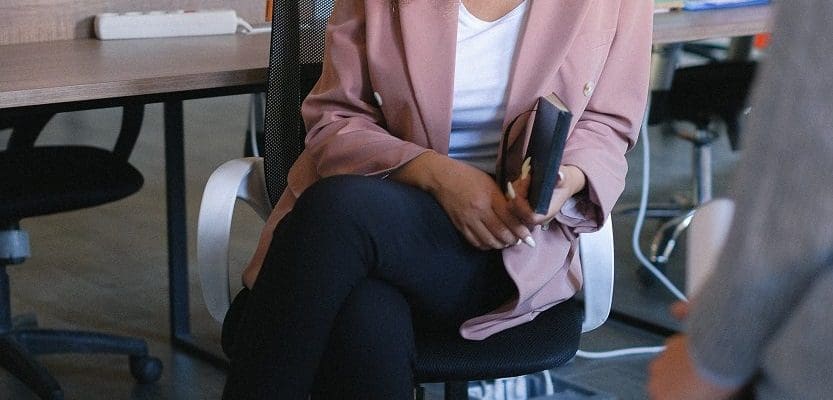 woman sitting on office chair looking at camera in front of desk