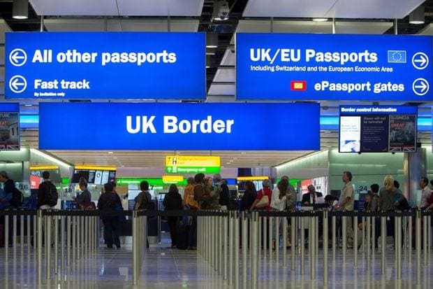 people in airport terminal with blue signs overhead