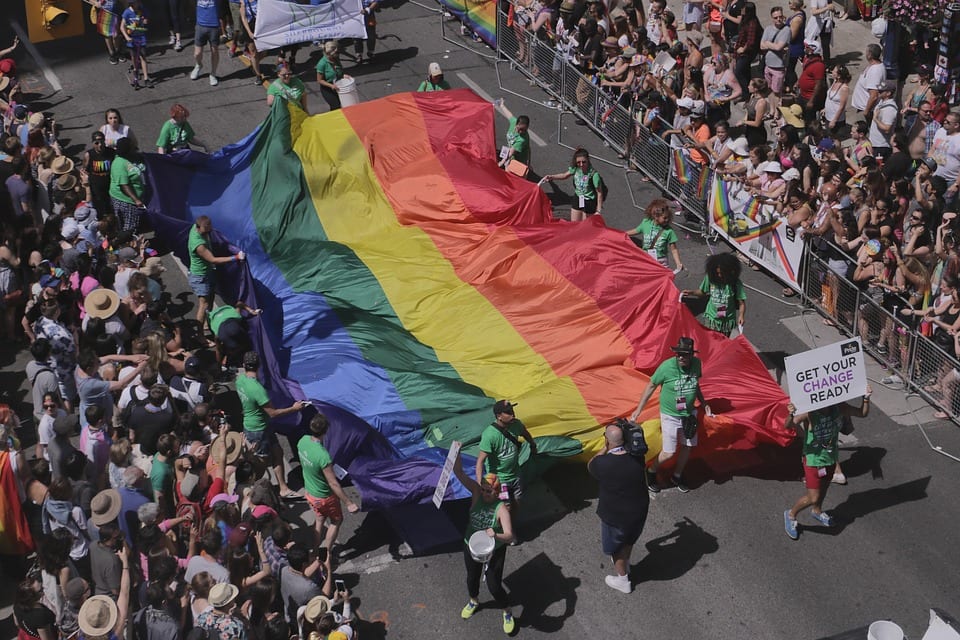 Pride event with walkers carrying large rainbow flag