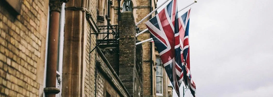 two UK flags hoisted on a balcony