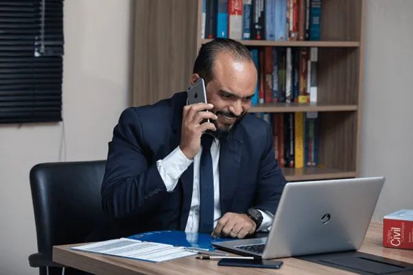 Man on his phone, using laptop on desk